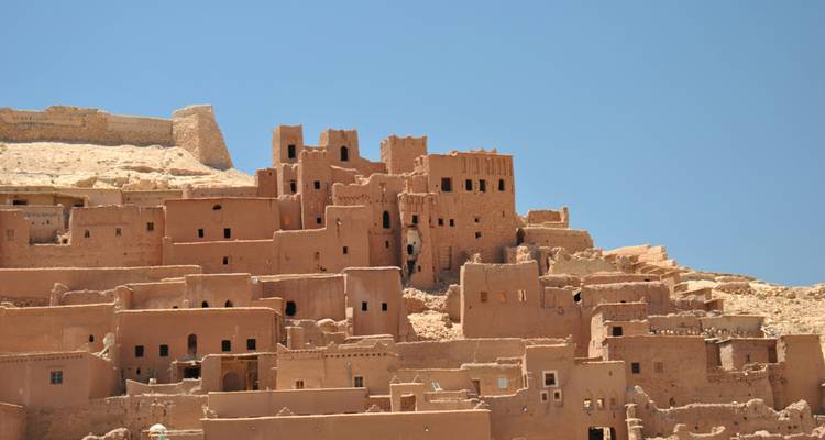 Earthen kasbah buildings of Ait Benhaddou rise against a clear blue sky