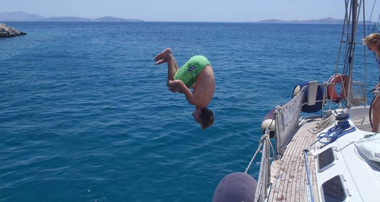 Persona saltando de un barco al mar con agua azul cristalina.