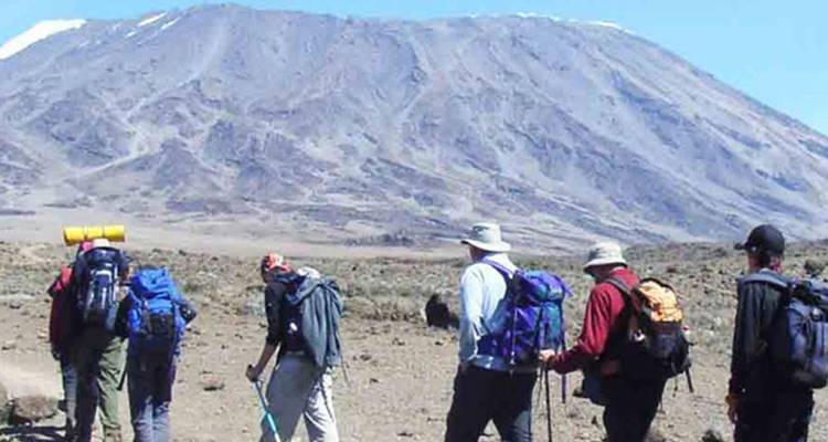 Des randonneurs marchant vers le mont Kilimandjaro avec des sacs à dos.