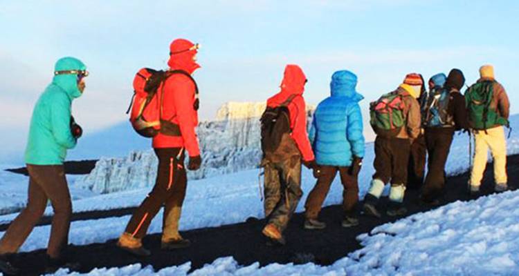 Randonneurs en tenues colorées traversant un paysage enneigé.