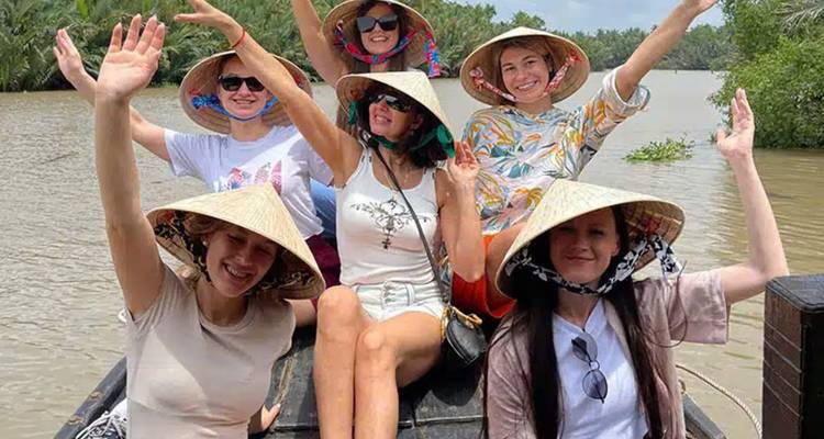 Smiling group of women on a boat ride wearing hats.