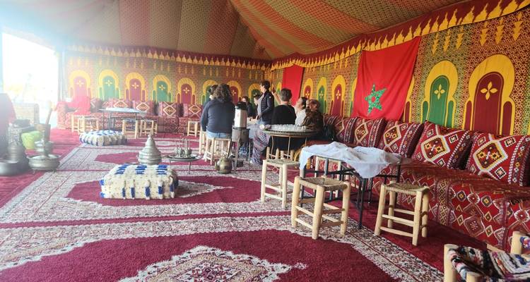 Un groupe de personnes assises à l'intérieur d'une tente décorée avec un décor marocain.