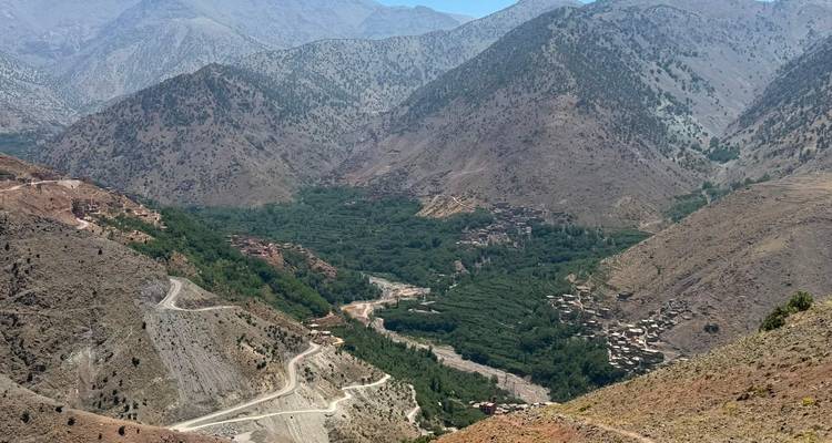 Vue panoramique des routes sinueuses en montagne et des villages verdoyants nichés dans la chaîne du Haut Atlas au Maroc.
