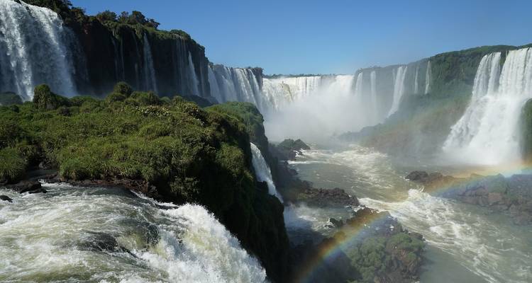 The powerful Iguazu Falls with lush greenery and rainbow.