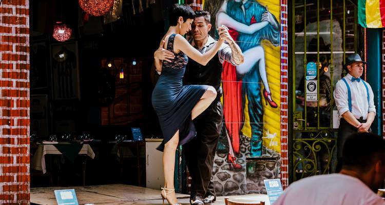 A couple performing a tango dance in a lively street setting.