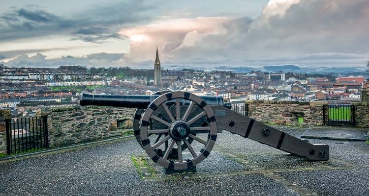 A cannon overlooking the city with a church spire in the background.
