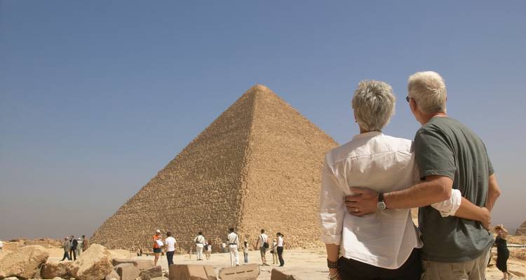 Ouder stel dat elkaar omhelst terwijl ze een enorme piramide op de archeologische site van Giza bewonderen.