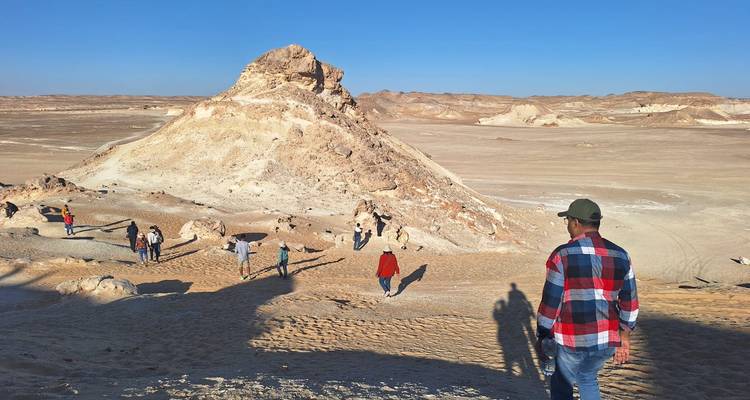 De petits groupes explorent une colline de craie en forme de dôme s'élevant de la plaine désertique aride de l'Égypte.