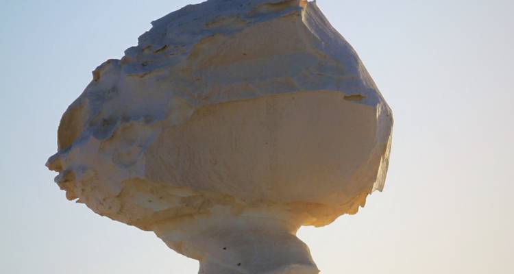Gros plan d'une roche de craie en forme de champignon brillant à la douce lumière du soir dans le Désert blanc.