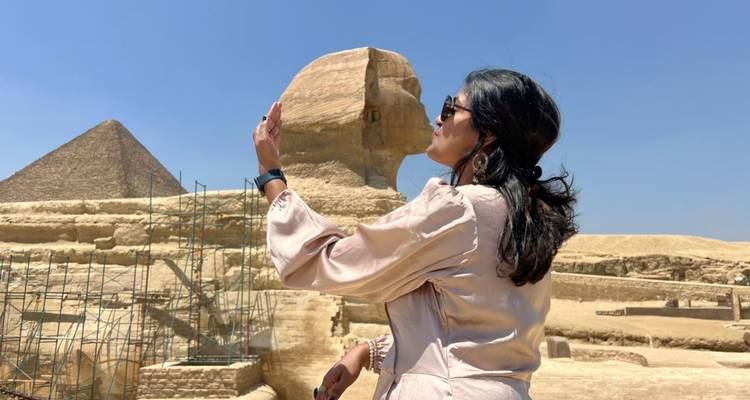 Un touriste encadre avec humour un selfie avec le Sphinx, la pyramide et l'échafaudage de restauration en arrière-plan.