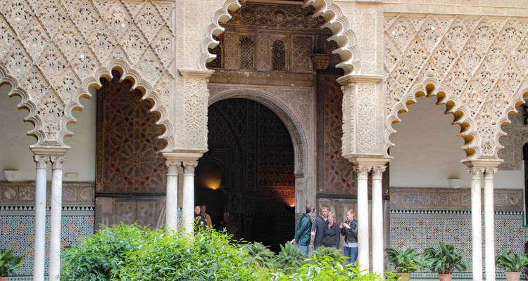 Intricate Moorish arches and columns with people standing.