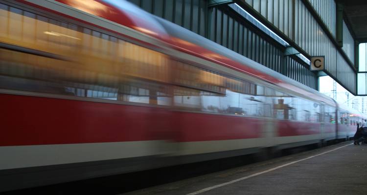 Blurred image of a red and white train in a station.