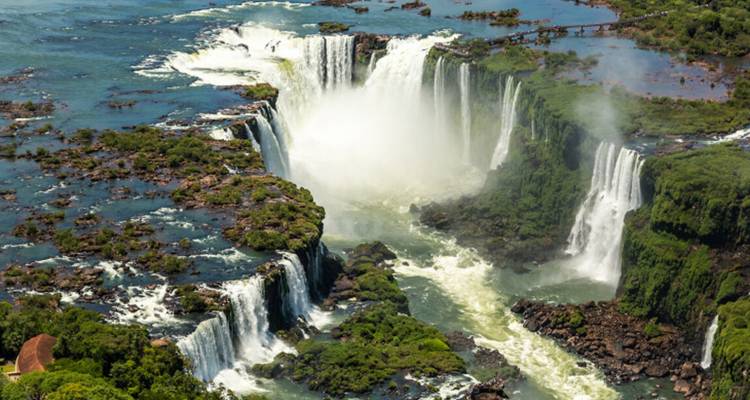 Dramatic aerial of horseshoe-shaped Iguazu Falls with mist rising above turquoise water