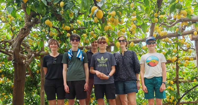 Una familia de pie bajo un dosel de limoneros en una huerta en la Costa de Amalfi.