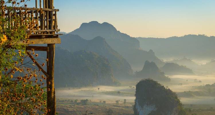 Paysage montagneux brumeux avec une plateforme d'observation en bois.