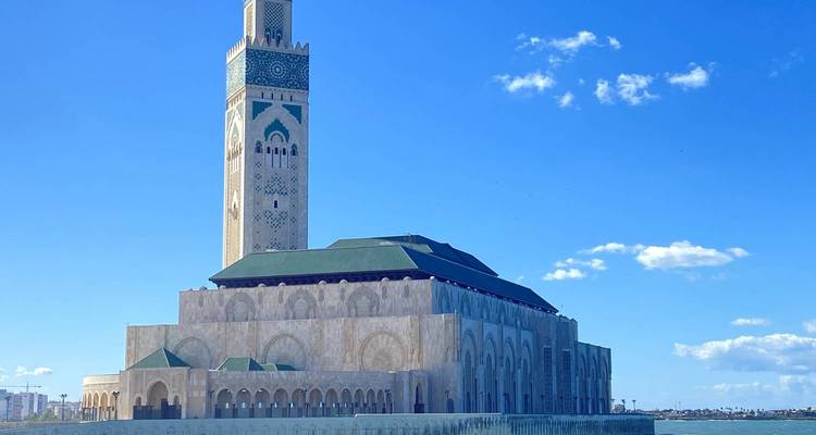 A large mosque with a tall minaret under a bright blue sky.
