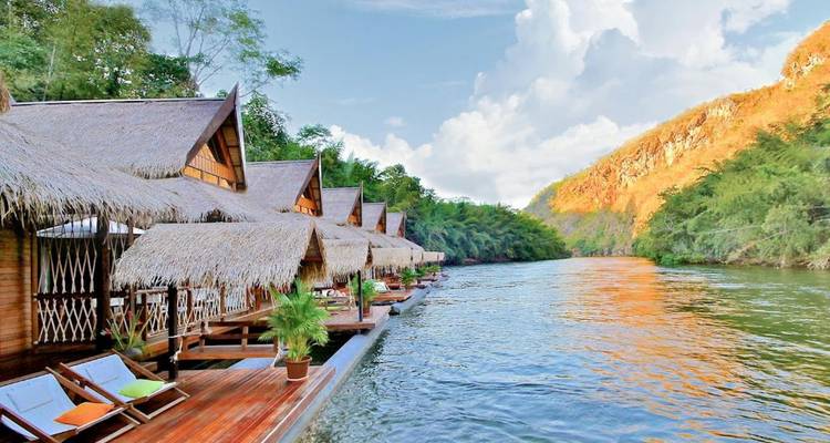 Bungalows flottants le long d'une rivière sereine entourée de collines.