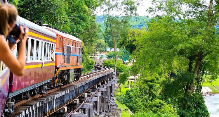 Photographe capturant un train coloré sur un pont historique.