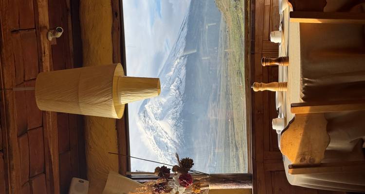 Configuración de comedor cerca de una ventana con vista a una montaña cubierta de nieve.