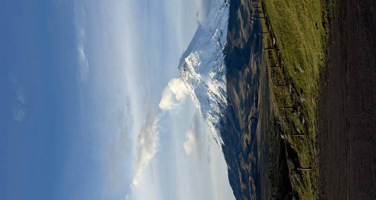 Paisaje abierto con un sendero que conduce a una montaña con cima nevada.