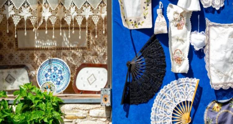 Craft market window with intricate lace, fans and ceramic plates displayed against a blue cloth
