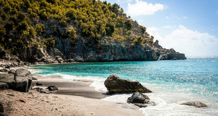 Scenic beach with crystal clear water and rocky cliffs.