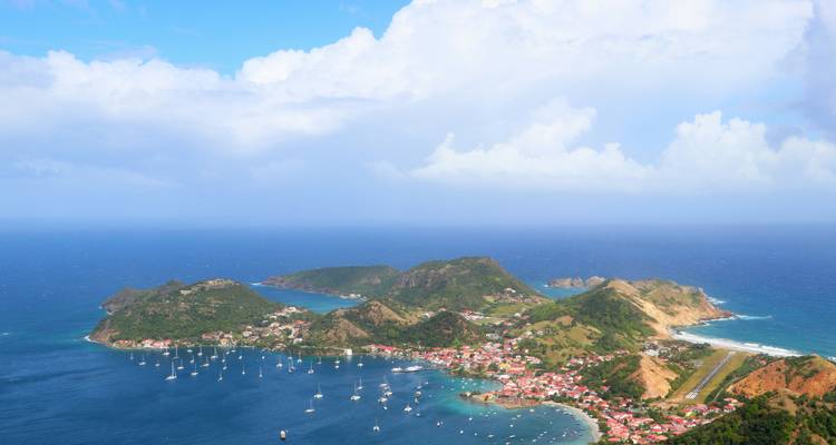 Aerial view of an island with boats and a village by the sea.