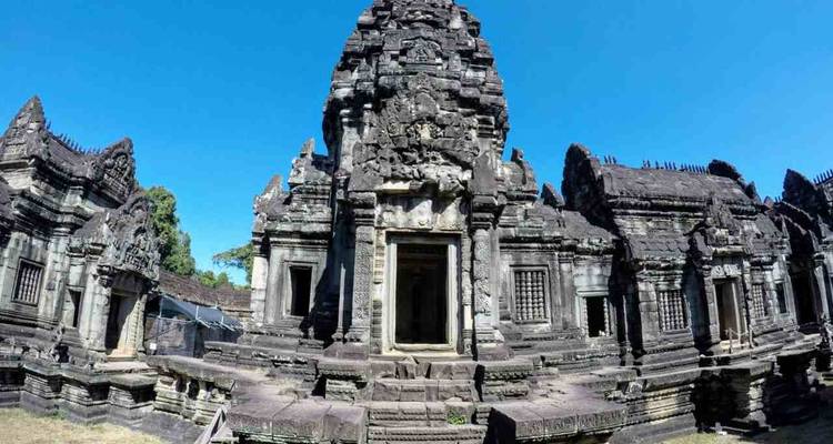 Ruines d'un temple historique en pierre avec des sculptures complexes sous un ciel bleu dégagé.