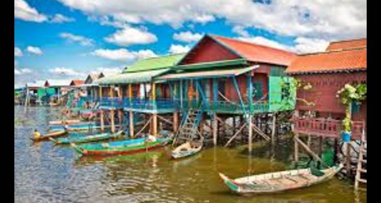 Des maisons sur pilotis colorées le long de l'eau, avec des bateaux amarrés à un quai.