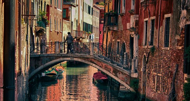 Charmanter Kanal in Venedig mit einer Fußgängerbrücke und bunten Gebäuden.