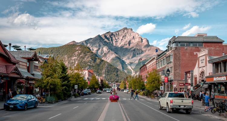 Calle principal muy concurrida de Banff llena de tiendas y enmarcada por los imponentes picos de las Montañas Rocosas