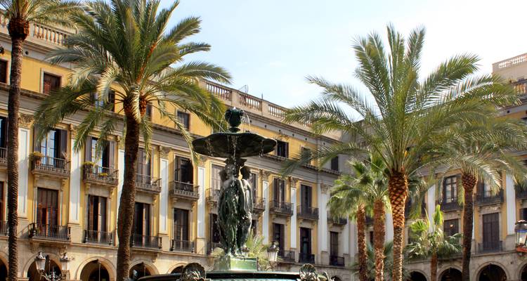 Place élégante avec une fontaine entourée de palmiers et de bâtiments historiques.