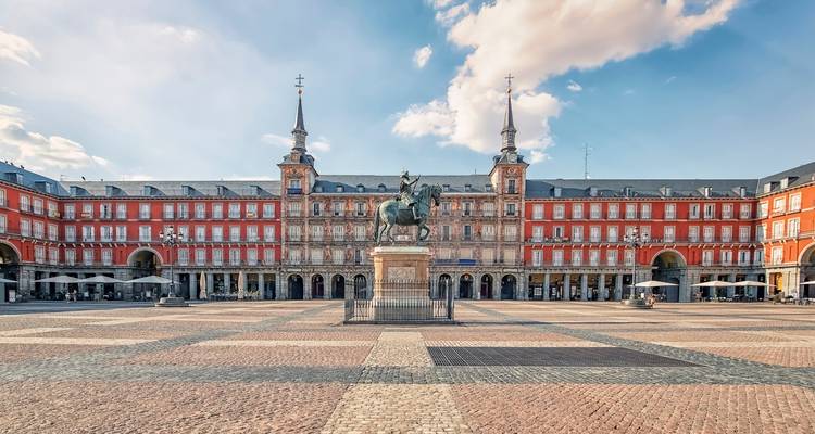 Grande place avec une statue au centre entourée d'architecture historique.