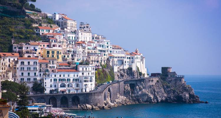 Witte en pastelkleurige huizen tegen de kliffen van Amalfi die naar de Middellandse Zee afdalen langs een dramatische kustweg.
