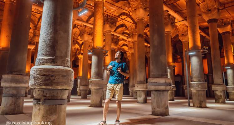 A traveller with a backpack stands among the illuminated columns of Istanbul’s Basilica Cistern.