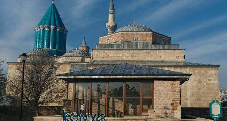 Exterior del Museo Mevlana en Konya con su distintiva cúpula cónica turquesa bajo el cielo azul.