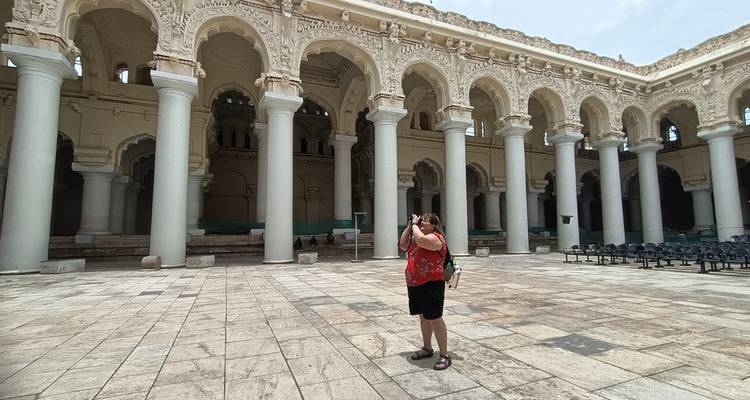 A person taking photos inside a historical building with ornate columns and arches.