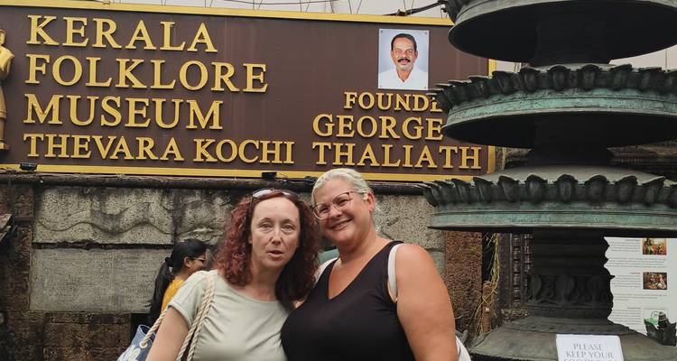 Two women posing in front of the Kerala Folklore Museum entrance.