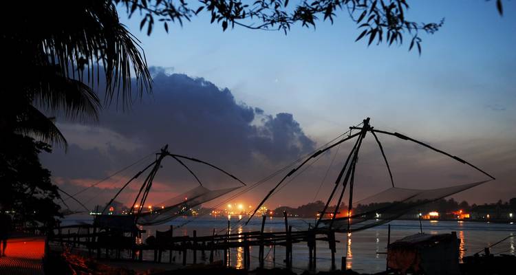 Traditional Chinese fishing nets along the waterfront at dusk.