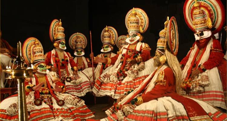 Performers in traditional Kathakali costumes on stage.
