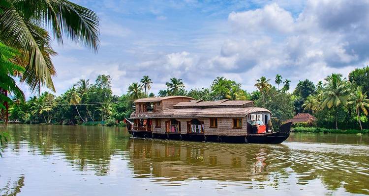 Houseboat cruising on a calm river surrounded by lush greenery.