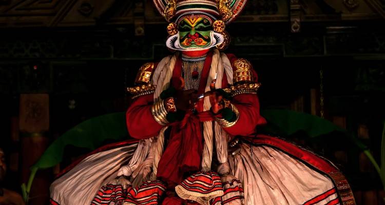 Kathakali performer in elaborate makeup and costume on stage.