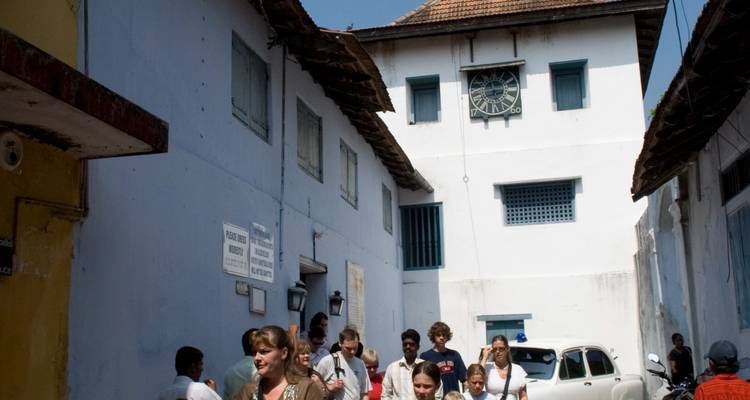 Narrow street with group of people and a clock tower in the background.