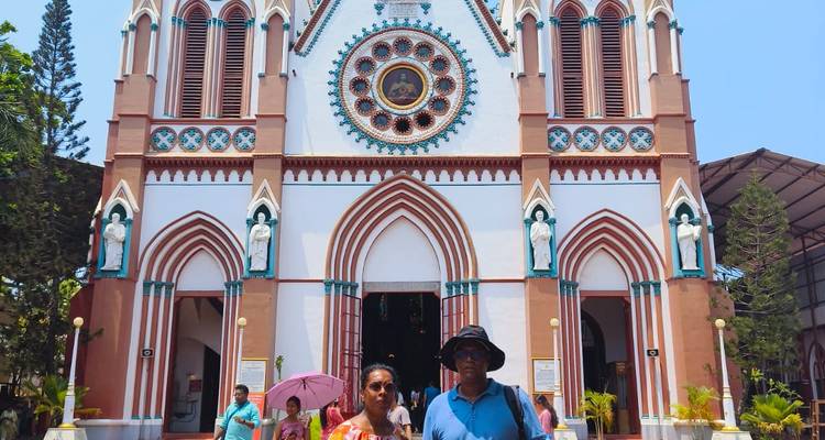 Couple posing in front of a colorful cathedral with Gothic architecture.