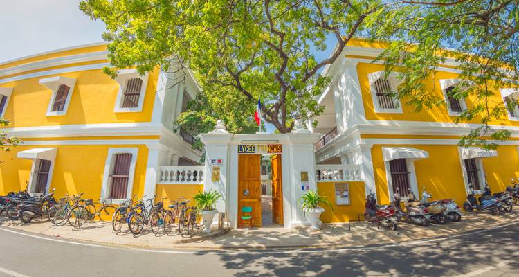 Vibrant yellow colonial building with bicycles parked outside.