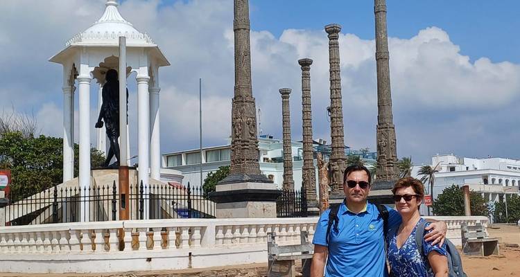 Couple posing in front of monuments with pillars and a statue.