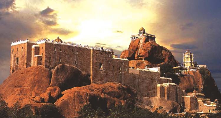 Temple complex built on rocky hill under dramatic sky.