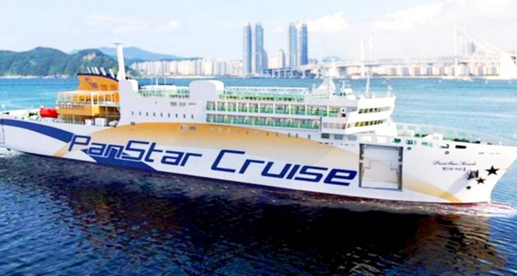 A cruise ship named PanStar Cruise with cityscape in the background.