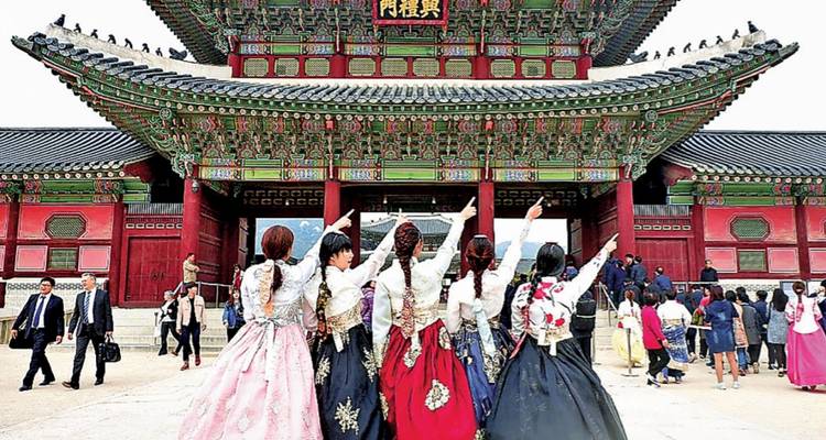 People dressed in traditional clothing facing a colorful palace.