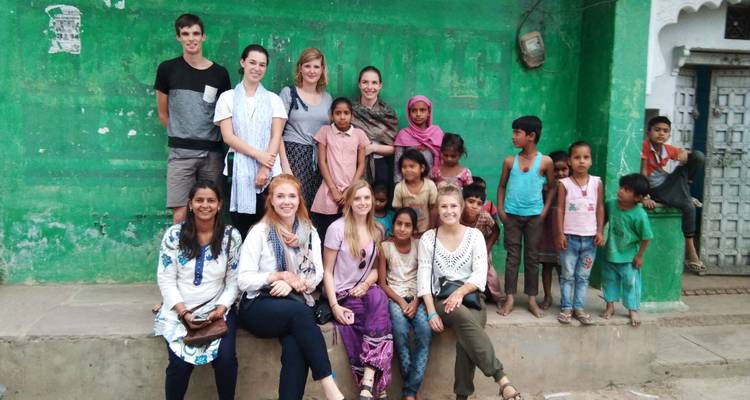 Group of tourists and children sitting and standing on a ledge in a street.